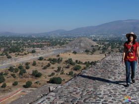 Raquel en lo alto de la pirámide del templo del Sol con la pirámide del templo de la luna al fondo - Teotihuacán - México