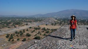Raquel en lo alto de la pirámide del templo del Sol con la pirámide del templo de la luna al fondo - Teotihuacán - México